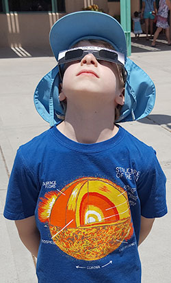 boy enjoying the view of the sun with solar viewing glasses